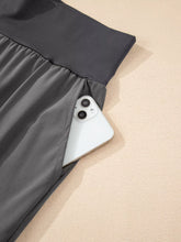 A sleek dark gray athletic skirt featuring a smooth fabric and elastic high waist pocketed design
