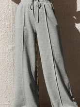 Gray wide leg drawstring waist pants with subtle side seam detailing and a comfortable drawstring waistband