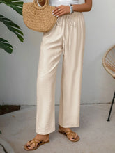 Beige drawstring wide leg pants with subtle textured fabric and machine wash cold care instructions