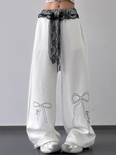 White wide leg pants with black lace belt trim and delicate bow embroidery on each leg for elegant styling