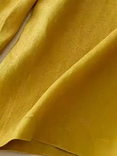 Golden-yellow silk wide-leg pants with a subtle textured weave and decorative button detailing