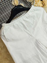 White cotton elastic waist pants with waistband hanging on black hanger machine wash cold recommended