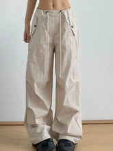 Beige relaxed wide-leg drawstring pants with cargo flap pockets and drawstring waist for casual comfort