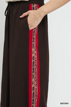 Umgee wide leg pants in brown with bold red side stripe and intricate black and beige beadwork detail