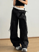Black cargo pants with bow elastic waist, white elastic waistband, multiple side pockets, and frayed drawstrings for an edgy look