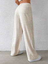 Beige linen wide-leg pants with a relaxed fit and single front pocket offering comfortable wide leg style
