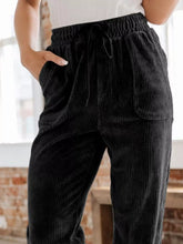 Black corduroy pants with elastic waistband and drawstring featuring a relaxed fit for comfortable wear