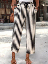 Black and white vertically striped wide-leg cropped pants with high waist and drawstring waistband