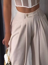 Beige high-waisted wide leg pleated pants with a white belt buckle for a stylish and elegant look