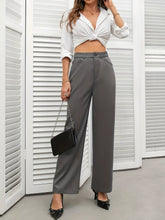 Black chain-strap handbag with a sleek rectangular body complementing high waist wide leg pants outfit
