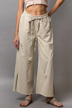 Beige pol distressed drawstring wide-leg trousers featuring distressed patches and a drawstring slit waistband