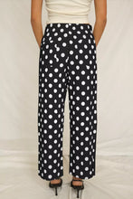 Black wide-leg polka dot print pants with bold white dots and patched pockets mid-rise straight leg design