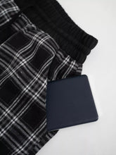 Navy blue textured leather wallet shown alongside relaxed fit plaid pants highlighting style and material contrast