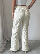 Cream-colored textured high waist wide leg trousers with elastic waistband and floral-patterned fabric