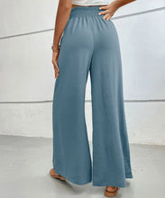 A pair of high-waisted wide leg pants in light blue with a gathered elastic waistband for comfortable wear