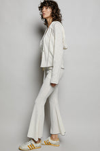 A woman wearing light gray textured ribbed knit hooded sweatshirt and matching ribbed knit flared pants