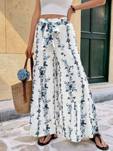 White floral print tie front wide leg pants with blue and black pattern and self-tie waistband