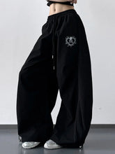 Black wide leg drawstring pants featuring heart-shaped embroidered patch on thigh in soft fabric design