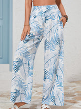 White wide-leg pants with vibrant blue tropical print and shirred waistband for a stylish tropical print shirred look