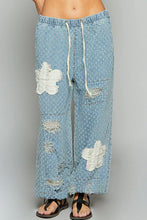 Light blue denim pol floral patch pants with white floral patches and distressed details in textured twill fabric