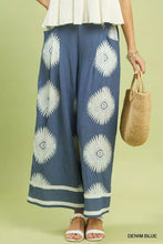 Denim blue umgee abstract border print wide leg pants with bold white sunburst pattern and light gray hem trim