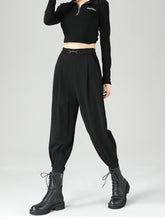 Black high-waisted tapered pants in polyester fabric with pleats and a metallic chain buckle for a perfect fit