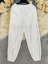 White cotton elastic waist pants with tapered cuffs featuring an elastic waistband suitable for machine wash cold