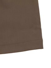 Brown woven fabric with neat stitched hem of wide leg drawstring pants showing durable detail