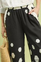 Black wide leg pants with white hexagon print and scalloped white elastic waistband by Umgee