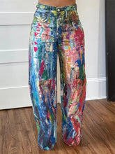 Vibrant wide leg pants in denim with a bold abstract paint-splatter design in blues reds greens and yellows