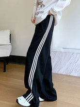 Black wide leg pants with three white striped wide side stripes in a comfortable track pant style