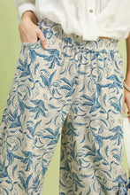 Beige linen printed wide leg pants with flowing blue botanical print and elastic waistband featuring raw hem