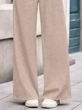 Beige wide-leg pants made of soft textured knit fabric with care instructions for machine wash