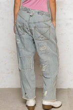 Light-wash denim distressed raw hem wide leg pants with vertical stripes frayed hems and distressed patches