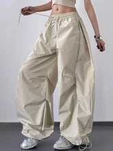Cream-colored glossy nylon oversized baggy wide leg cargo pants with elastic waistband and drawstring closure