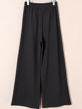 Black wide-leg sweatpants with tied elastic high waist and pleated detail in smooth flowing fabric