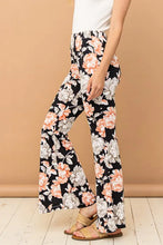 Black floral flare pants with peach and white blossoms made from wrinkle-free stretch fabric for comfort and style
