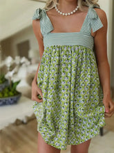 Green floral summer dress with ruffled hem, square neckline, and pearl necklace