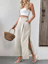Cream-colored slit wide leg pleated pants featuring high waist, front slit, and gold button detail