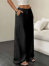 Black pleated tied wide leg pants with elastic waistband and side pockets offering stylish wide leg comfort