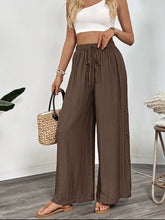 Brown casual wide-leg pants with high waist drawstring and subtle floral embroidery featuring care instructions
