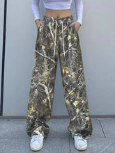 Relaxed fit camo print wide-leg pants with drawstring waist and side pockets in earthy green brown and yellow tones