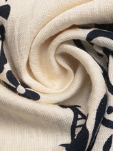 Cream-colored scarf with black botanical print complementing boho print wide leg pants for a stylish look