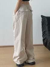 Beige relaxed wide-leg drawstring pants with elastic waistband and multiple cargo pockets for casual wear