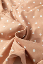 Soft peach-colored polka dot print drawstring wide leg pants with delicate white dot print and smooth fabric texture