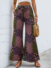 Floral high rise wide leg pants featuring a pink green and black patchwork design with small floral blossoms