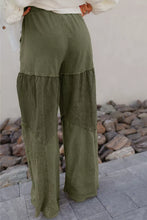 Olive green tiered wide leg pants featuring layered ruffle detailing and patchwork fabric panels