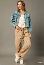 A woman wearing beige cargo-inspired drawstring pants with a light-wash denim jacket and white blouse