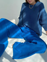 Blue ribbed knit sweater paired with wide leg pleated pants showcasing fabric texture and care instructions