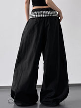 Black wide leg pants featuring a contrasting black and white checkered pattern waistband for stylish wear